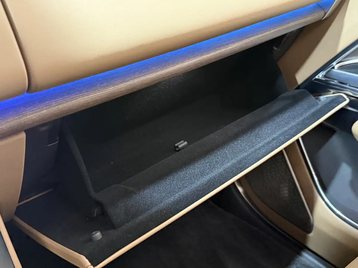 Vue intérieure rapprochée de la boîte à gants ouverte du Range Rover PHEV P550e Autobiography SWB 2024 avec finition cuir beige.