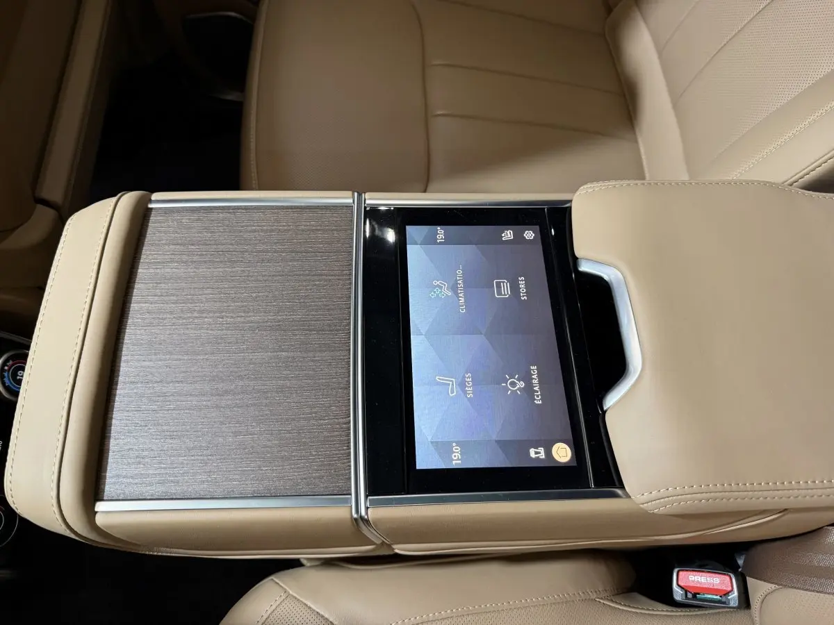 Vue rapprochée de la console centrale beige du Range Rover PHEV 2024 avec écran tactile intégré et finition bois.