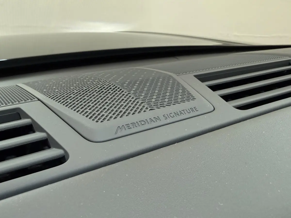 Gros plan sur la grille d'enceinte Meridian Signature intégrée au tableau de bord du Range Rover PHEV noir.