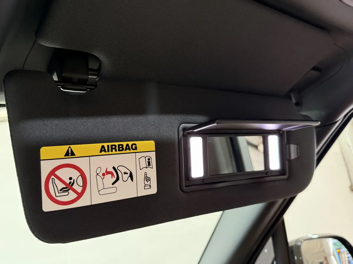 Pare-soleil côté conducteur noir avec miroir éclairé et étiquette airbag, intérieur d'un Range Rover PHEV 2024 noir.