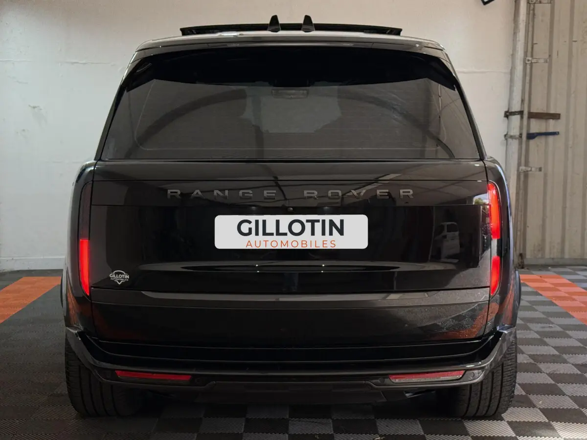 Vue arrière d'un Range Rover PHEV P550e Autobiography noir 2024 avec feux verticaux et logo visible.