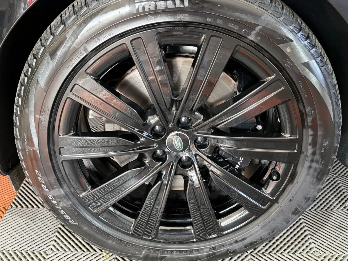 Gros plan sur la jante noire brillante de 22 pouces avec logo Land Rover au centre, montée sur pneu Pirelli.