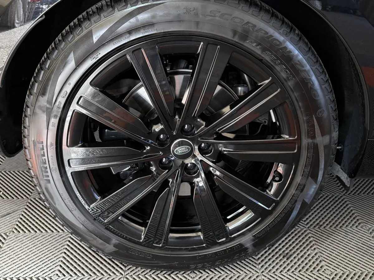 Gros plan sur la roue avant droite noire brillante du Range Rover PHEV P550e 2024 avec logo Land Rover central.