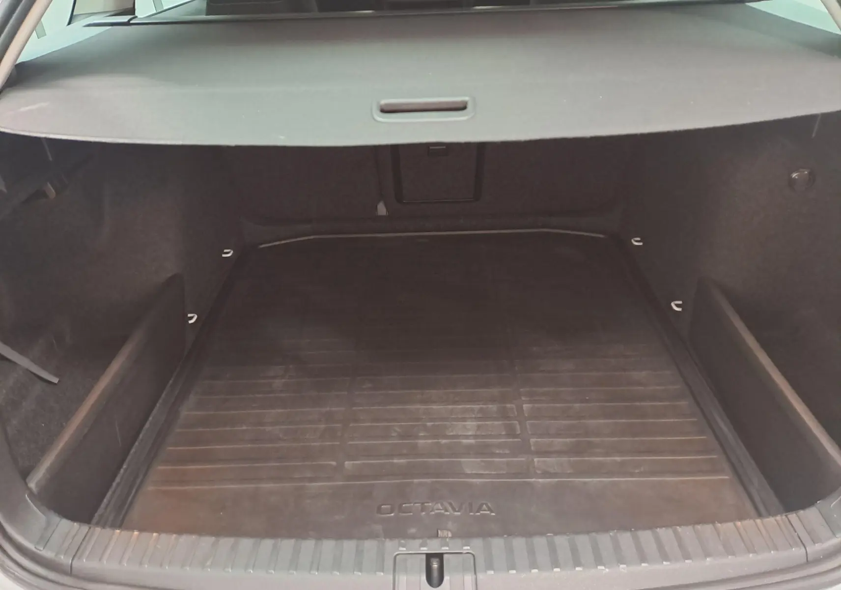 Vue intérieure du coffre spacieux d'une Skoda Octavia Combi 2025, avec tapis de sol noir marqué Octavia.