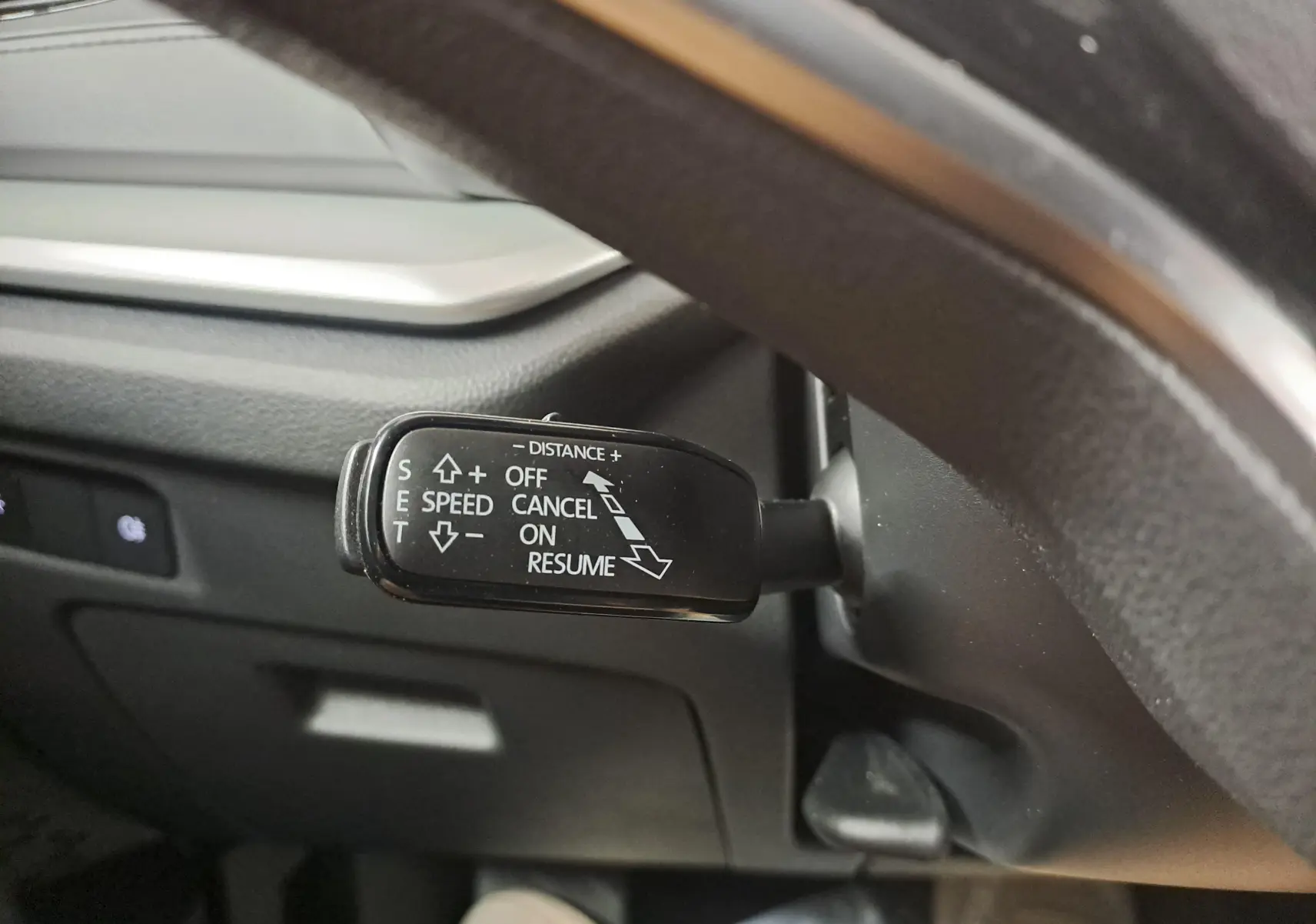 Gros plan sur le levier de régulateur de vitesse à gauche du volant dans une Skoda Octavia Combi blanc Moon.