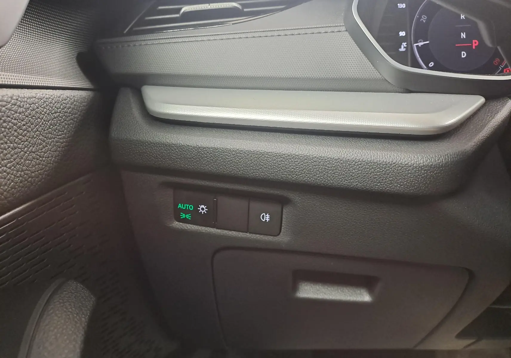 Détail intérieur côté gauche du tableau de bord de la Skoda Octavia Combi blanc Moon, avec commandes d’éclairage et indicateur digital.