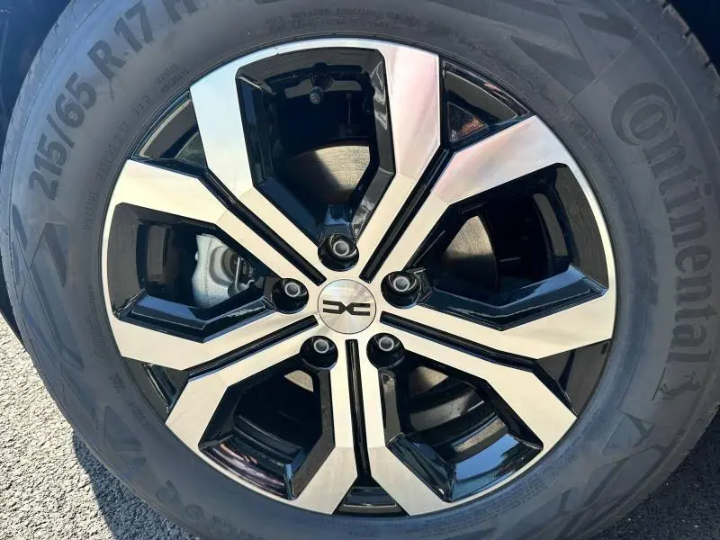 Gros plan sur la jante alu bicolore noire et argentée du Dacia Bigster blanc, montrant le logo central distinctif.