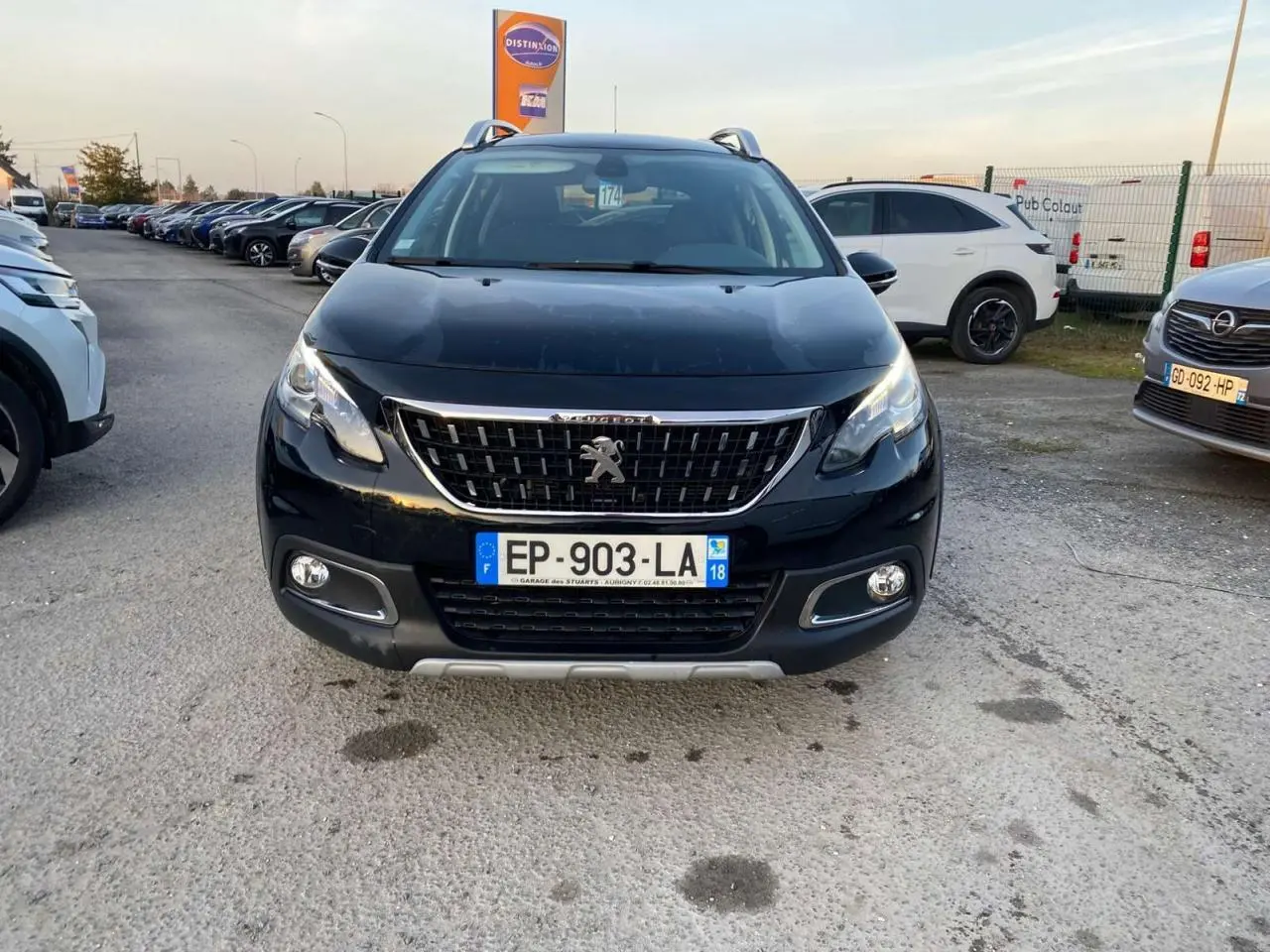 Vue frontale d'un Peugeot 2008 noir Perla Nera avec calandre chromée et feux diurnes LED allumés.