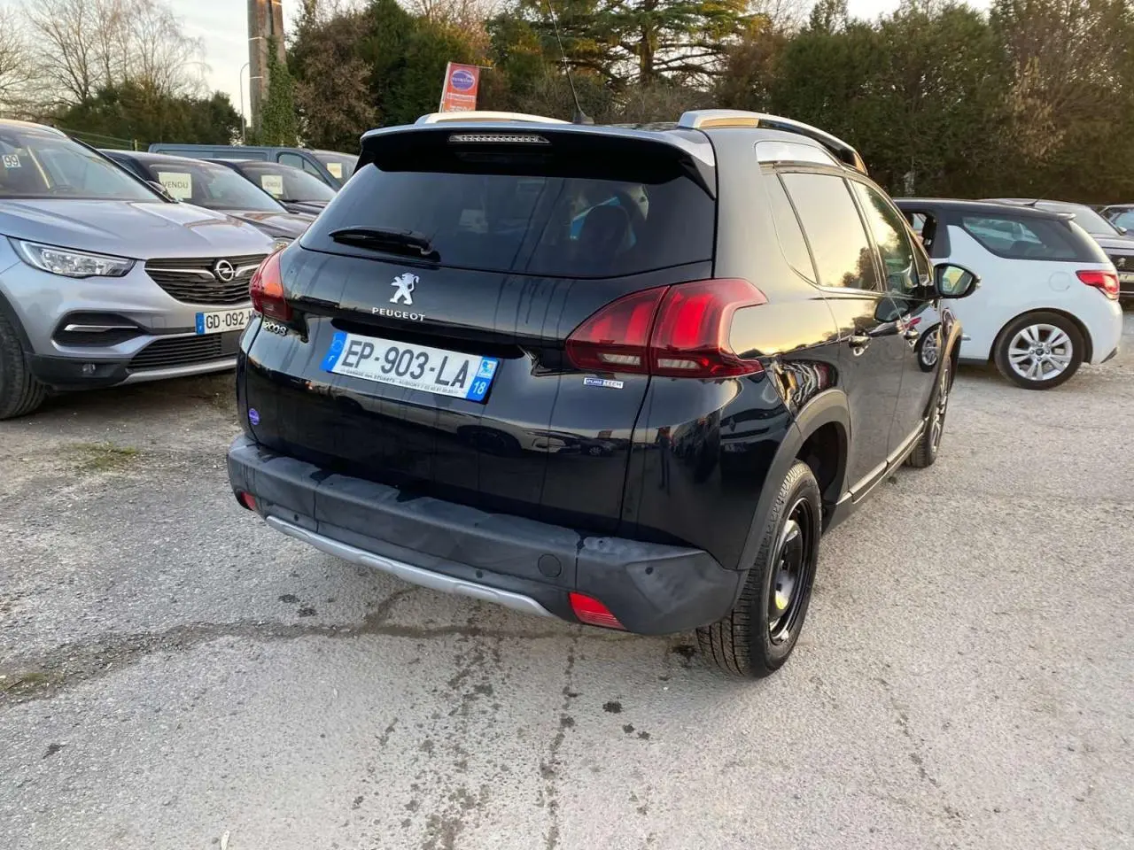 Vue 3/4 arrière droite d'un Peugeot 2008 noir Perla Nera avec feux arrière rouges et toit argenté.