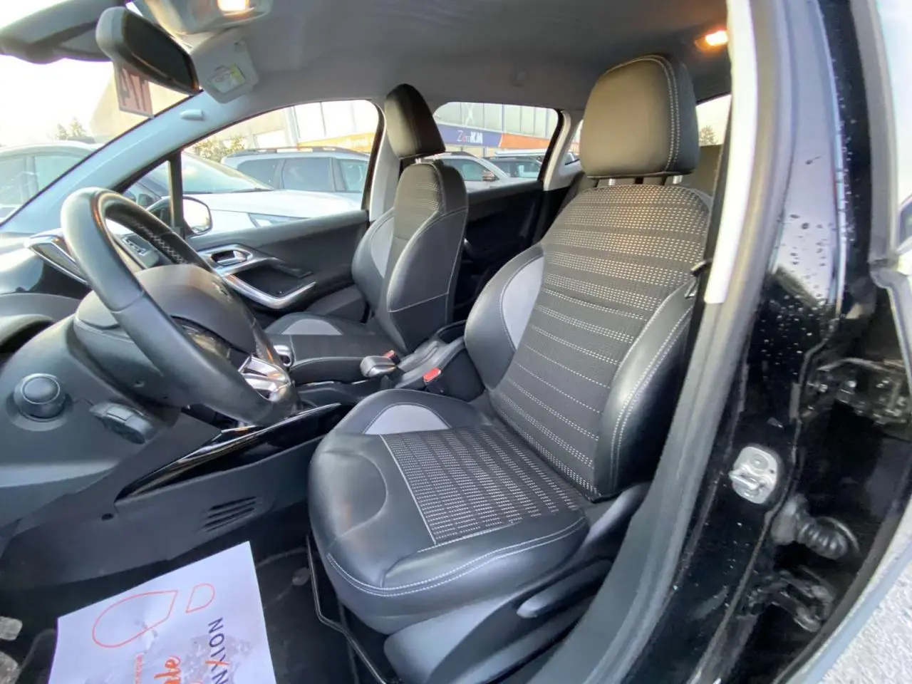 Intérieur côté conducteur d'une Peugeot 2008 noire, sièges sport en tissu et cuir avec coutures contrastées.