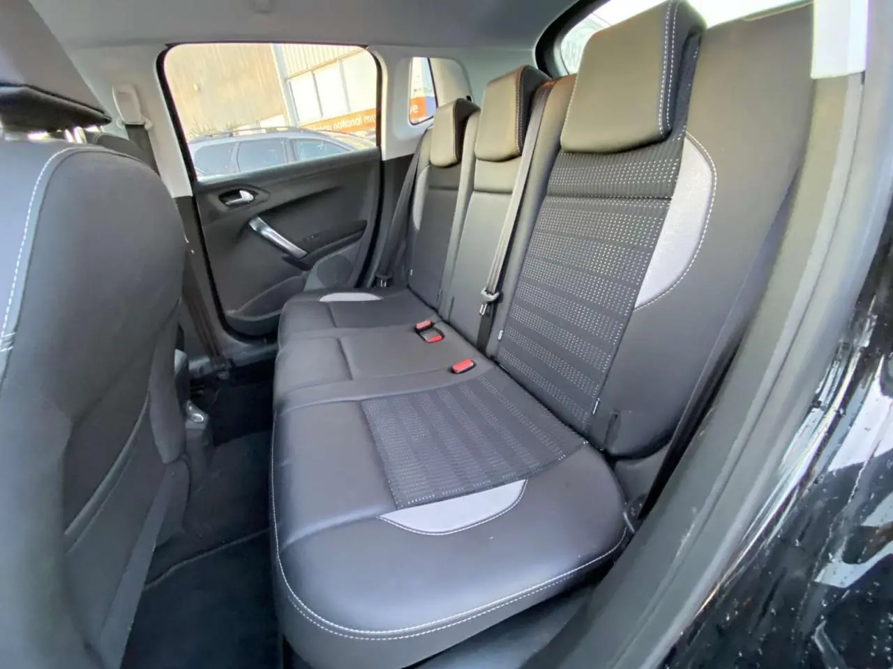 Vue latérale intérieure montrant la banquette arrière noire avec surpiqûres blanches du Peugeot 2008 noir Perla Nera.