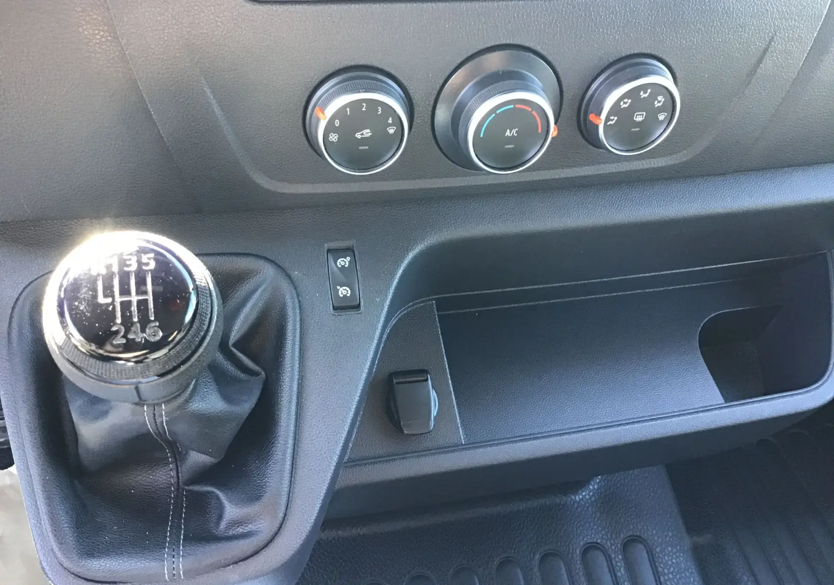 Vue rapprochée de la console centrale du Renault Master 2023 avec levier de vitesse manuel et commandes de climatisation.