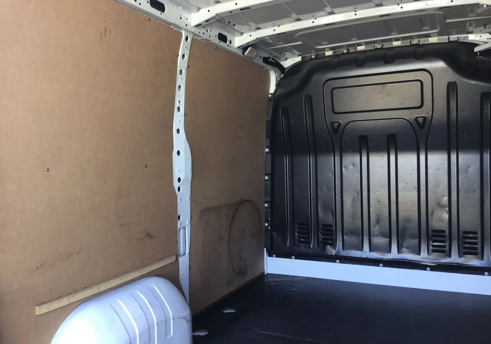 Vue intérieure de la zone de chargement du Renault Master blanc 2023, montrant les parois en bois et la cloison noire arrière.