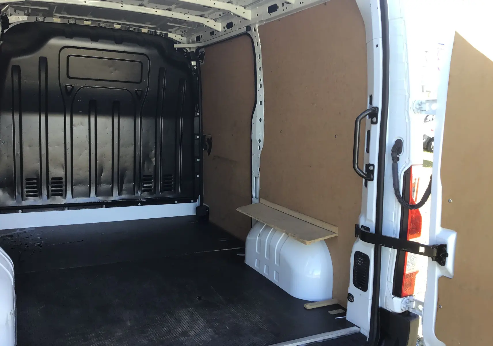 Vue intérieure arrière du Renault Master blanc L1H1 2023, montrant l'espace de chargement avec parois en bois et sol noir antidérapant.