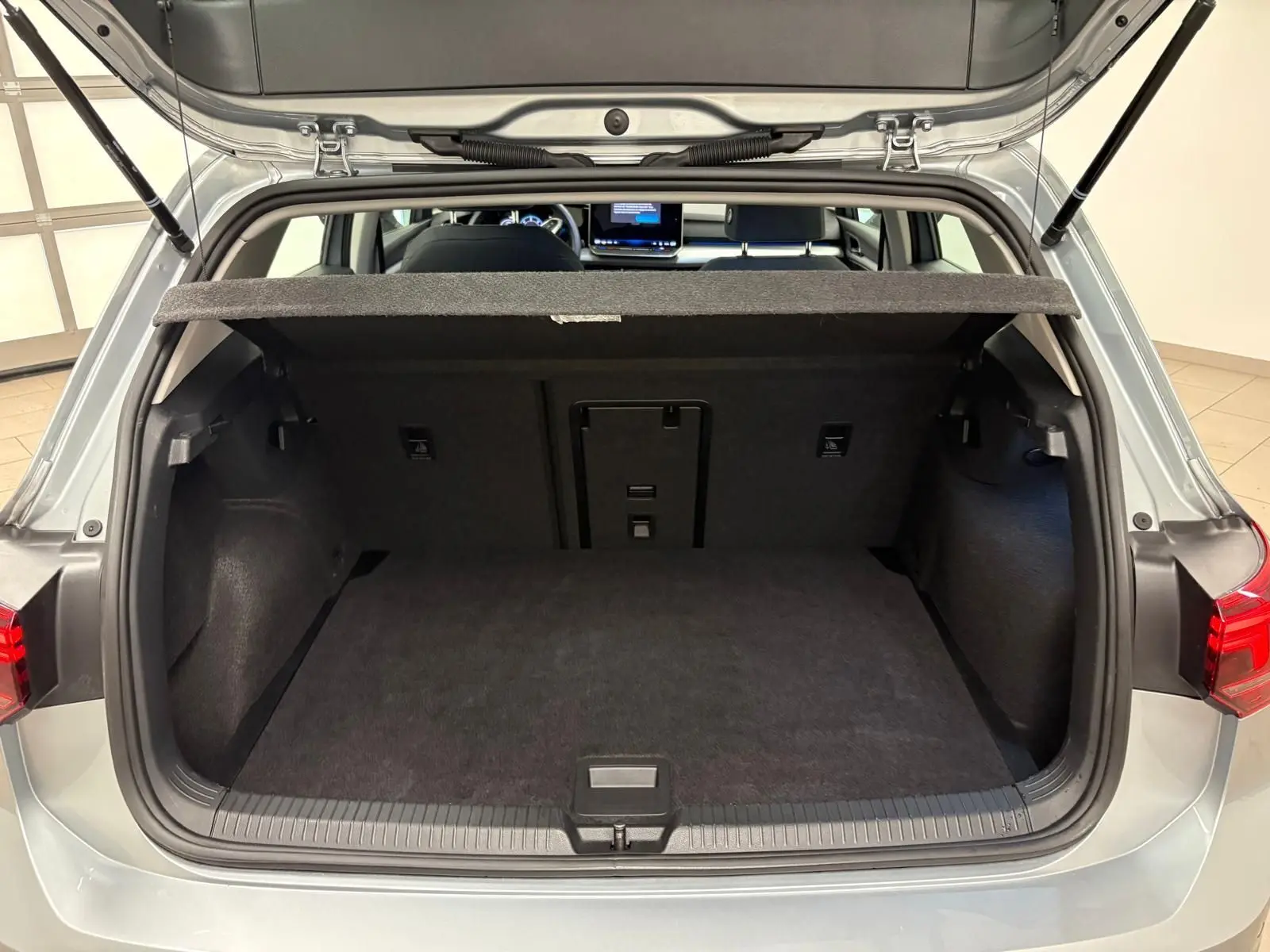 Coffre ouvert vue arrière d’une Volkswagen Golf 2.0 TDI 116 BVM6 Life Plus 2025 en reflet d’argent, intérieur noir.