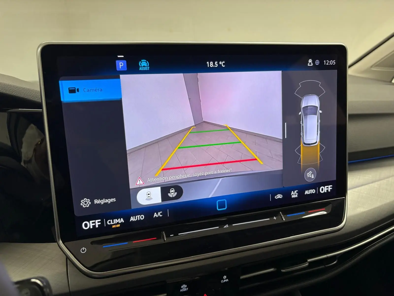 Vue intérieure sur l'écran tactile du système multimédia affichant la caméra de recul de la Volkswagen Golf 2025 reflet d'argent.
