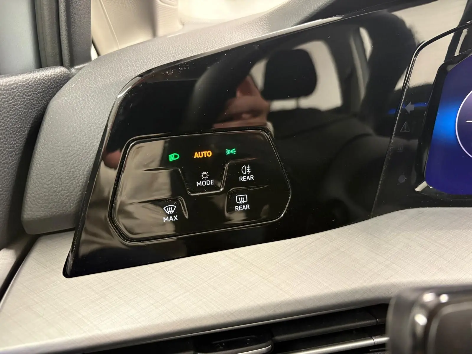 Gros plan sur les commandes d’éclairage et de désembuage du tableau de bord noir brillant d’une Volkswagen Golf 2025 couleur reflet d’argent.