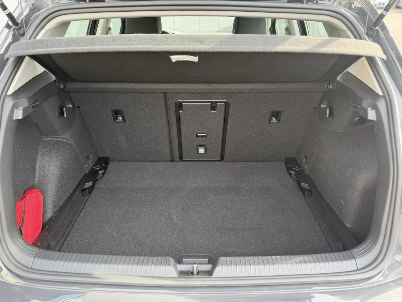 Coffre ouvert d'une Volkswagen Golf VIII gris Urano, montrant un espace de chargement propre et bien agencé.