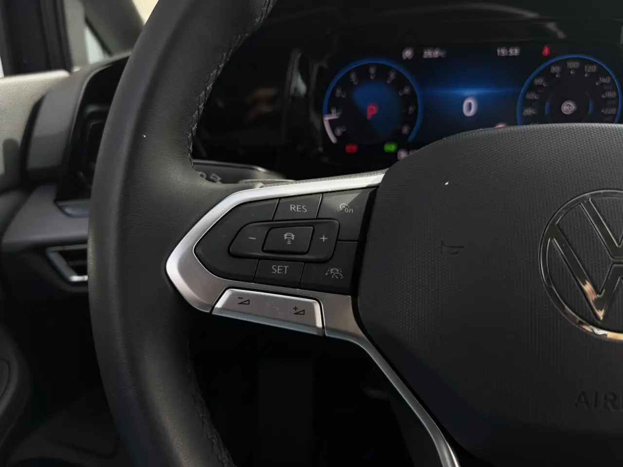 Gros plan sur le volant multifonctions cuir de la Volkswagen Golf VIII 2024 avec commandes intégrées et tableau de bord numérique.