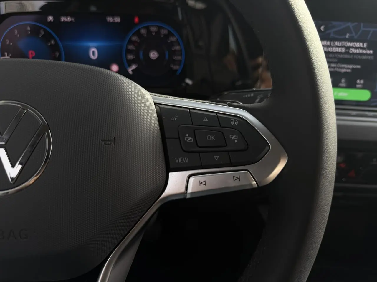 Gros plan sur le volant multifonctions cuir chauffant de la Volkswagen Golf VIII 2.0 TSI 190 DSG Style, avec tableau de bord numérique en arrière-plan.