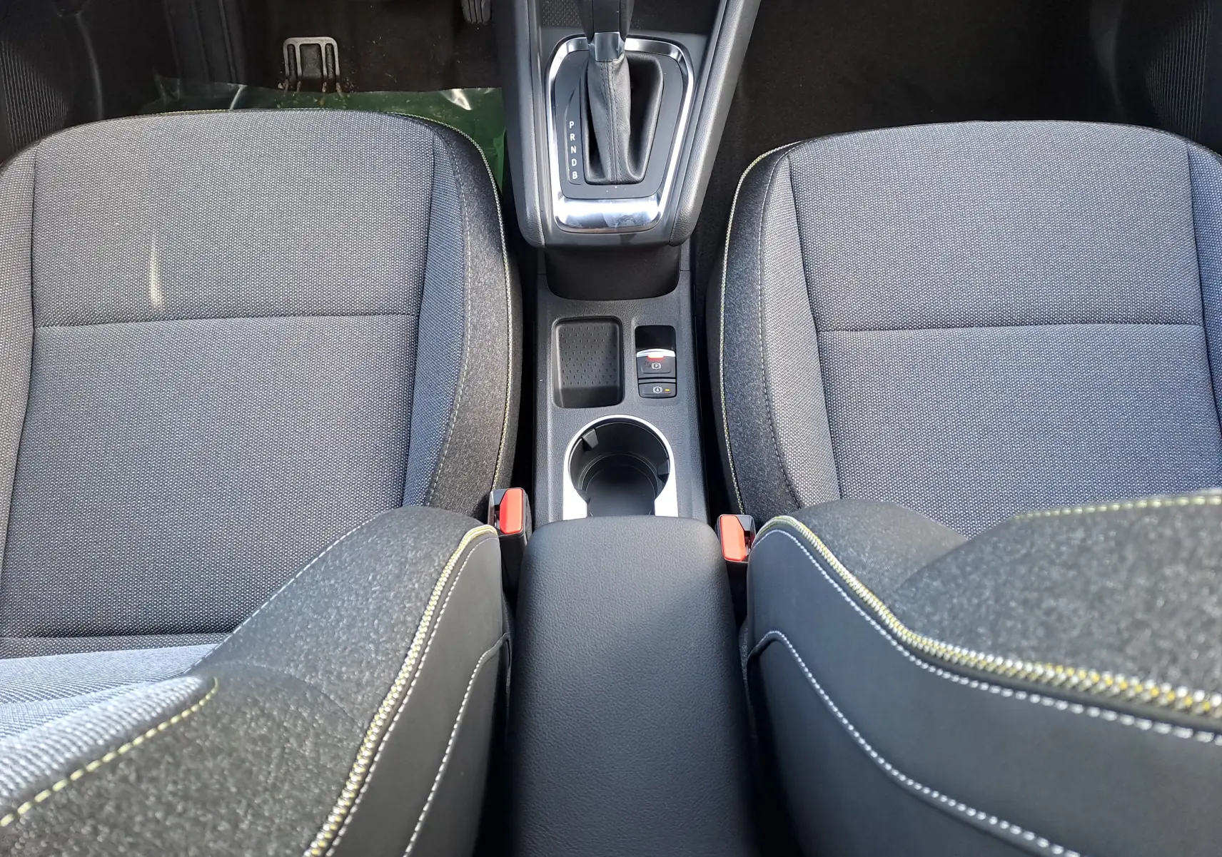 Vue plongeante sur la console centrale et les sièges gris tissu du Renault Captur hybride 2025 avec boîte automatique.