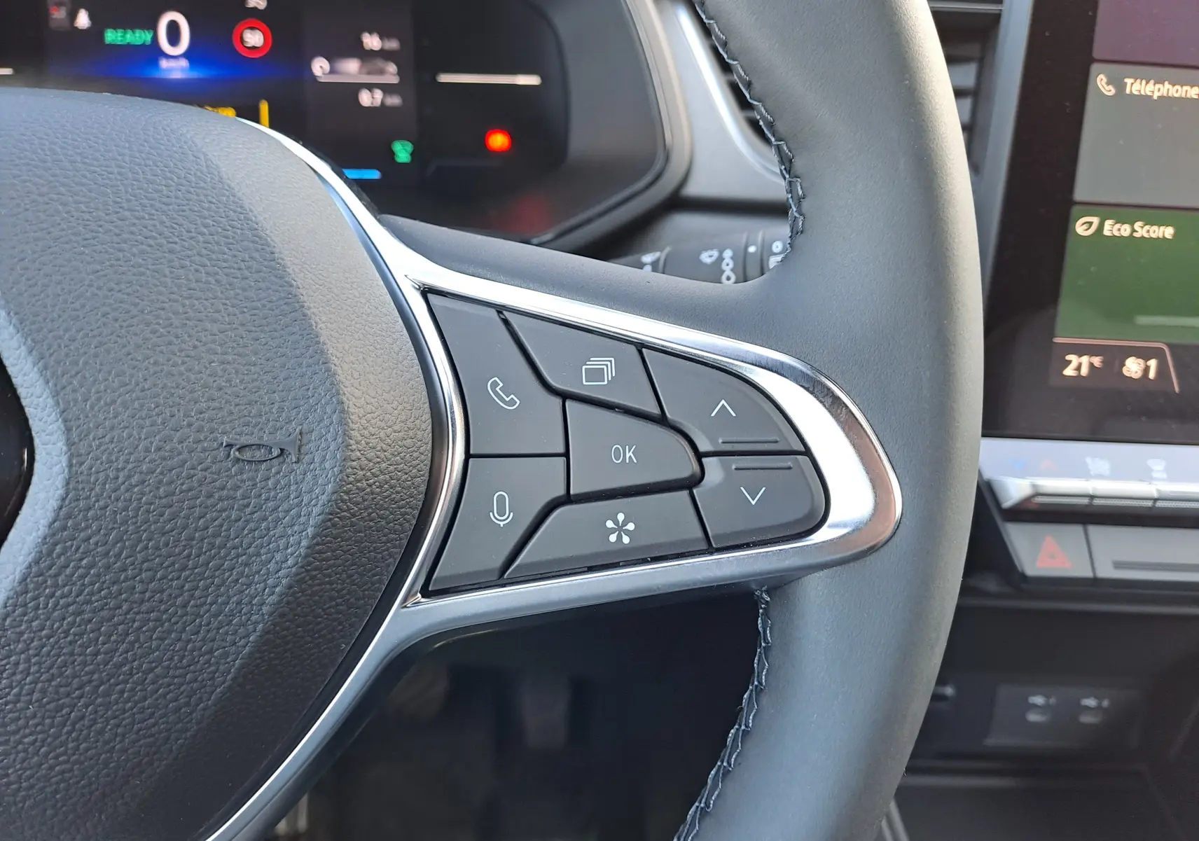 Gros plan sur les commandes au volant à droite du Renault Captur blanc nacré 2025, avec tableau de bord numérique en arrière-plan.