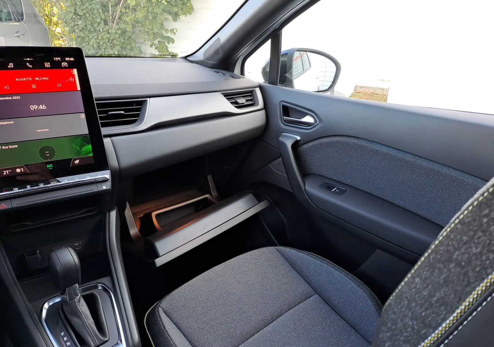 Intérieur avant droit du Renault Captur 2025 hybride, avec tableau de bord noir, écran tactile et boîte automatique visible.