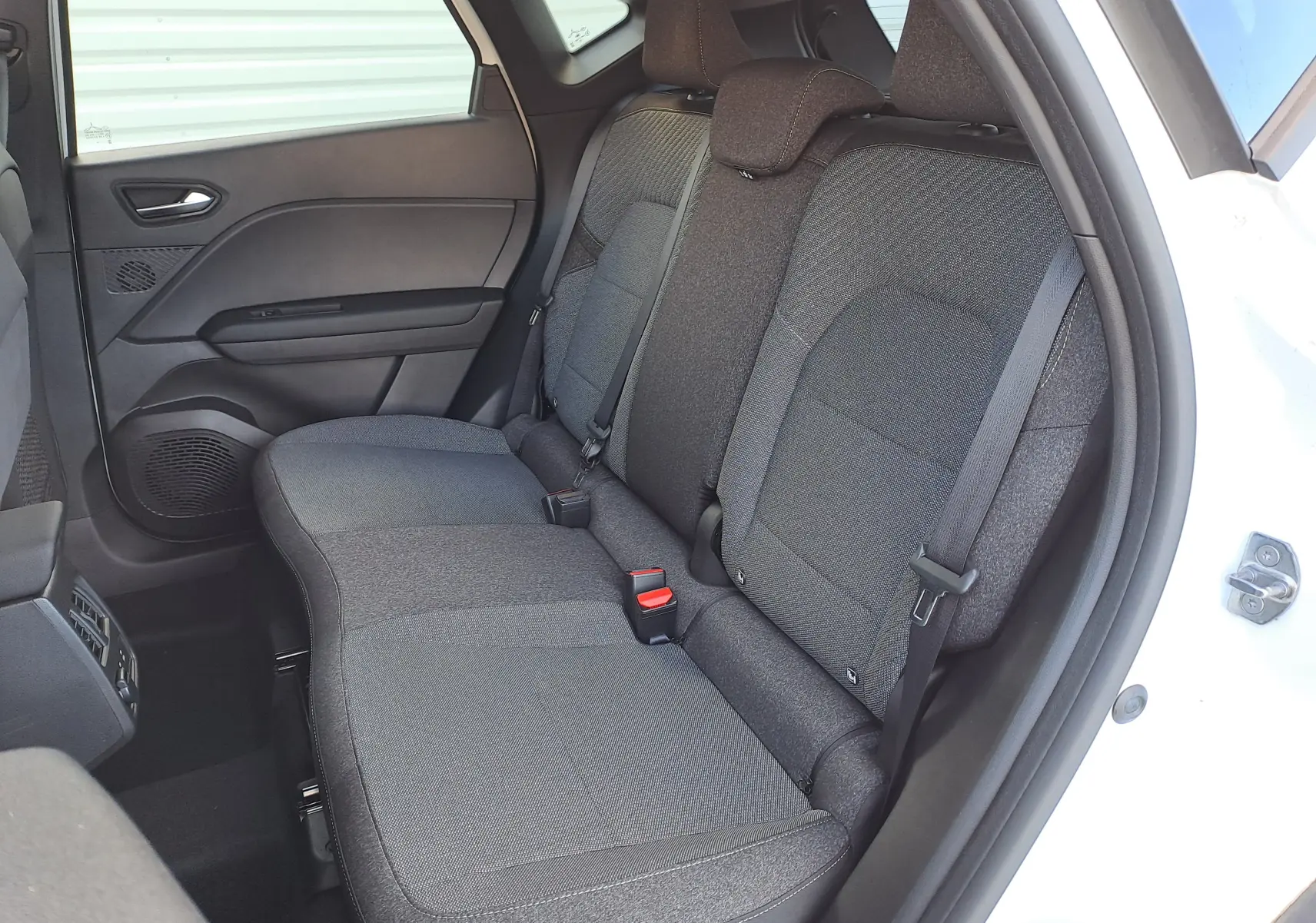 Vue côté droit de la banquette arrière gris foncé du Renault Captur 2025 blanc nacré avec porte ouverte.