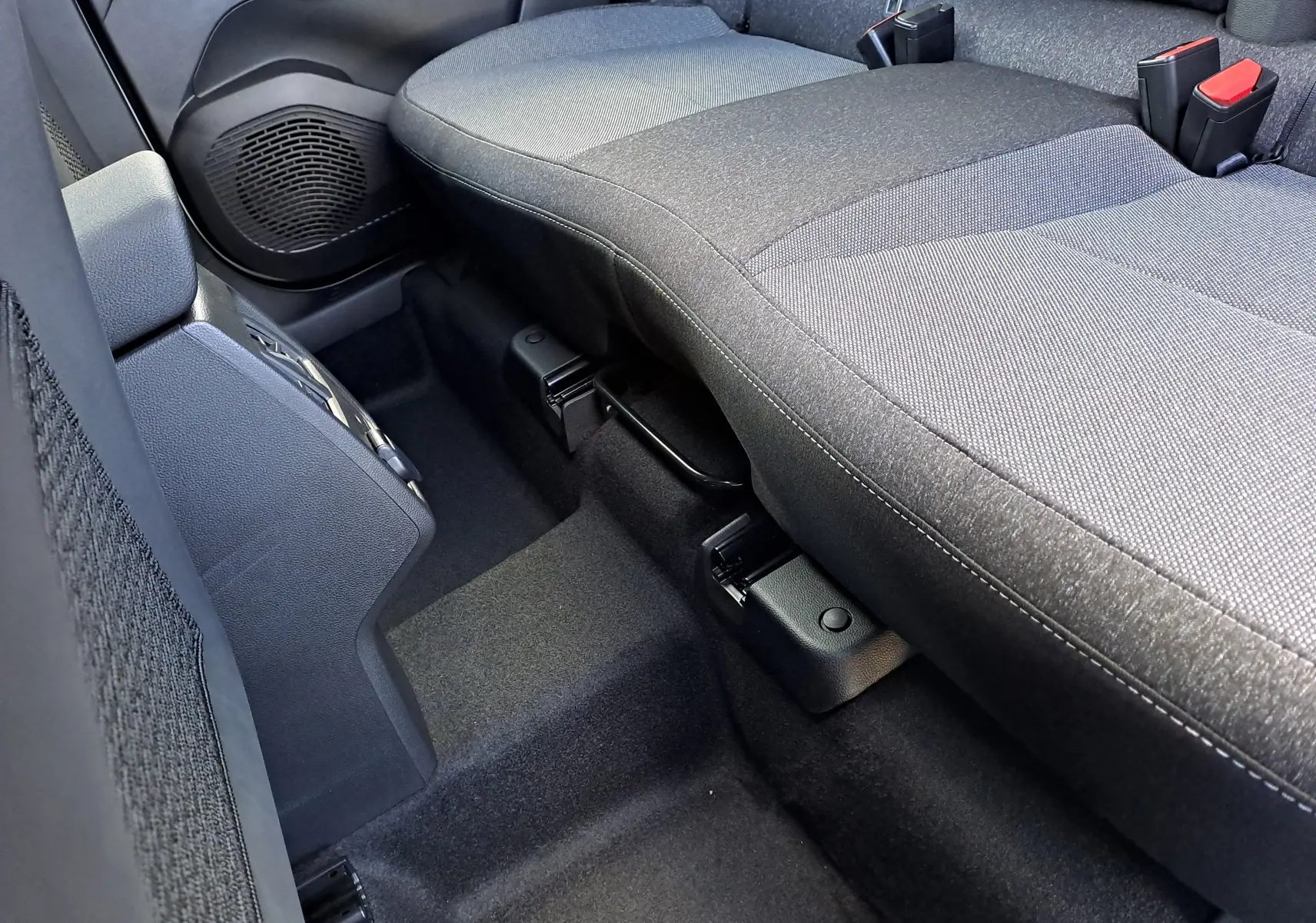 Vue rapprochée de la banquette arrière grise en tissu du Renault Captur 2025, mettant en valeur les ceintures de sécurité et le sol noir.