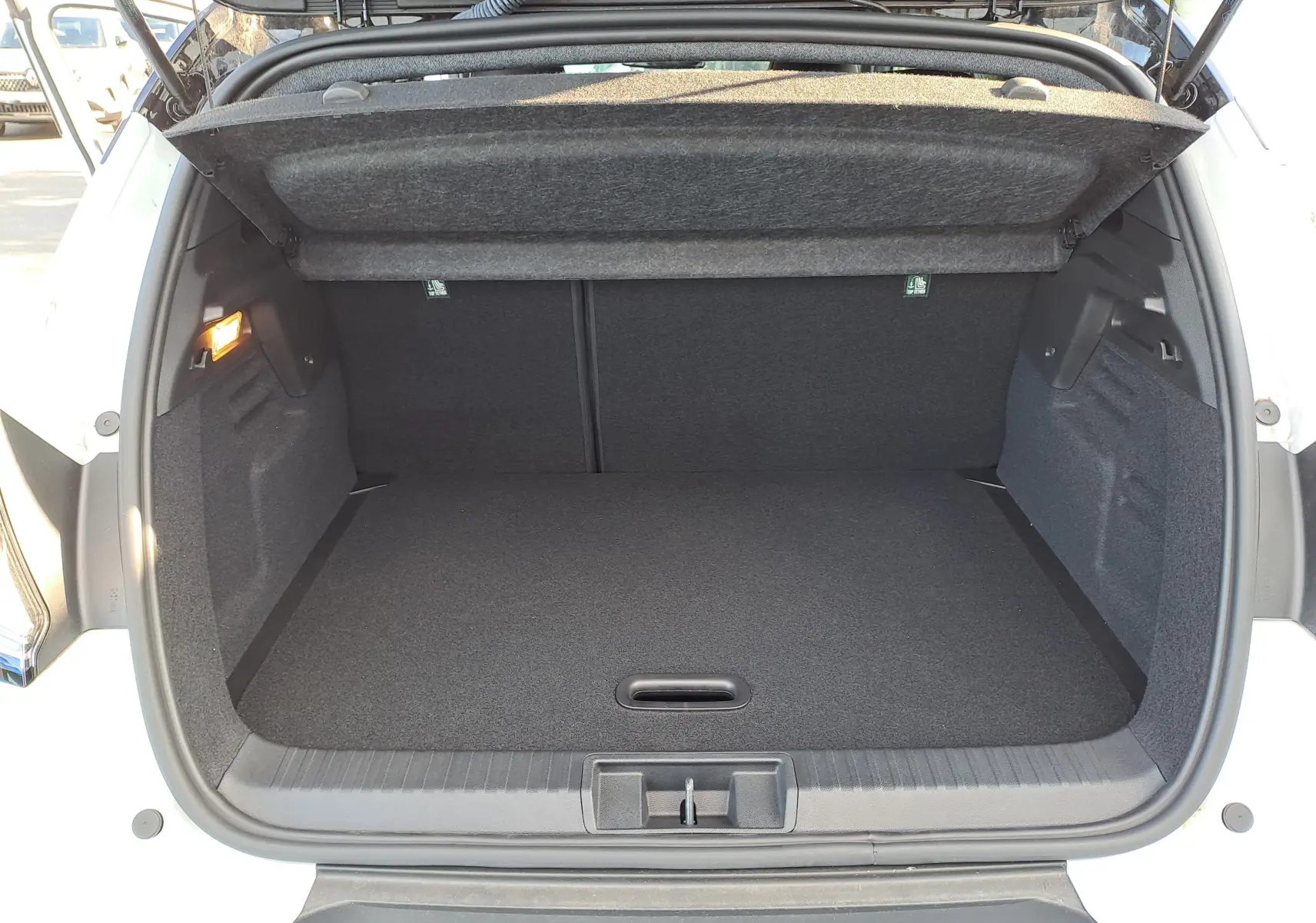 Coffre ouvert vu de l'arrière d'un Renault Captur blanc nacré avec toit gris Highland, espace de rangement vide et propre.