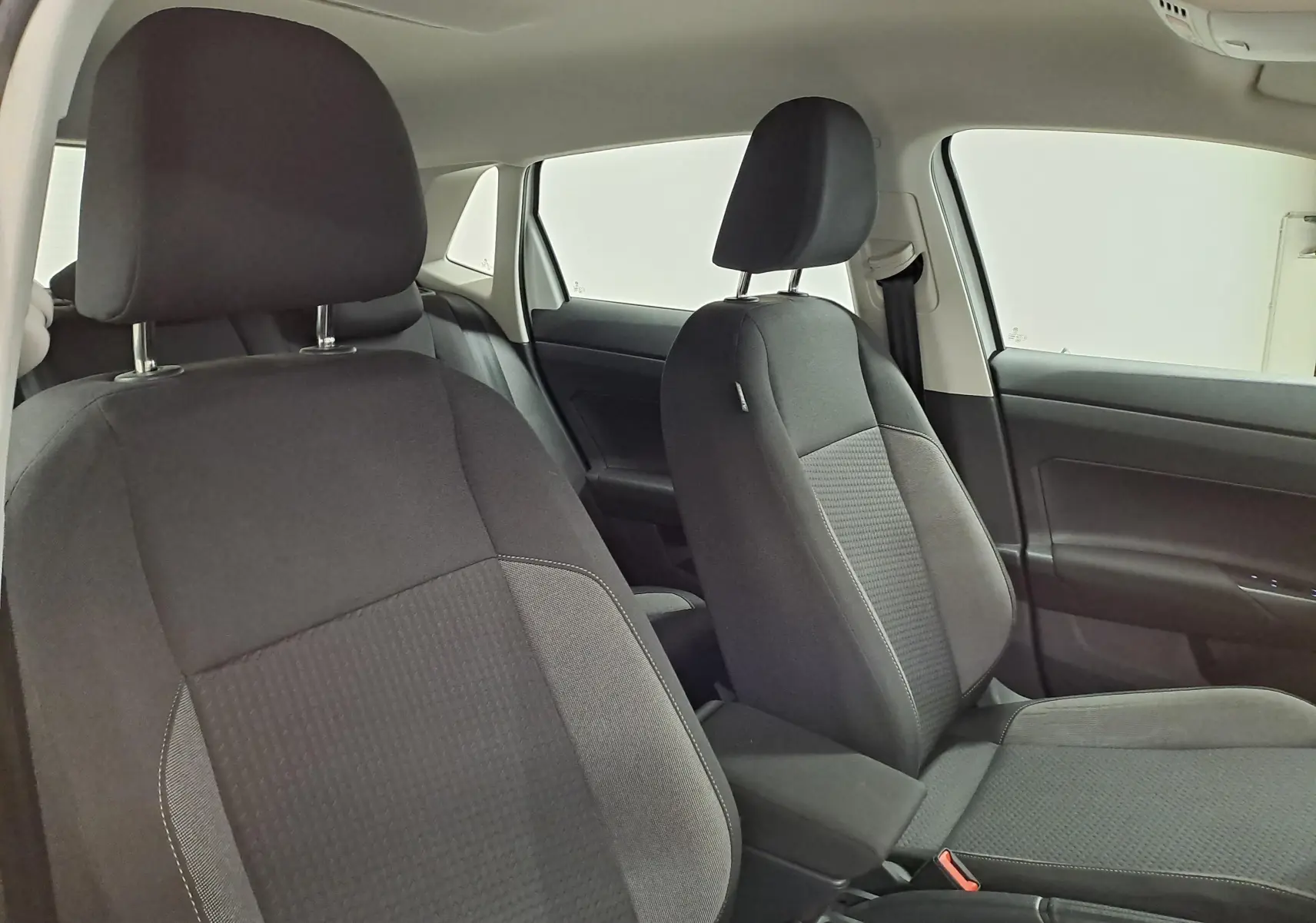 Vue intérieure des sièges avant noirs de la Volkswagen Polo 2024, version Life Plus, avec détails tissu et ceintures visibles.