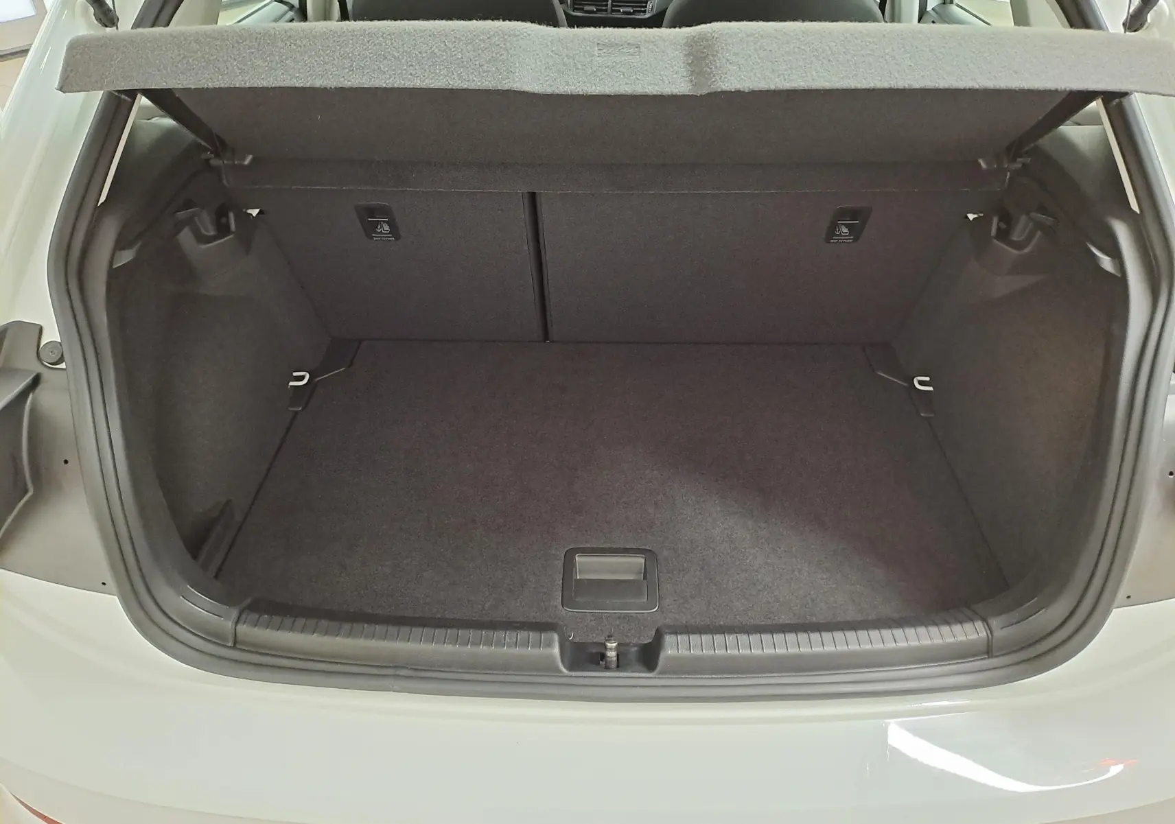 Coffre ouvert vu de l'arrière d'une Volkswagen Polo blanc pur 2024, montrant un espace de chargement propre et spacieux.