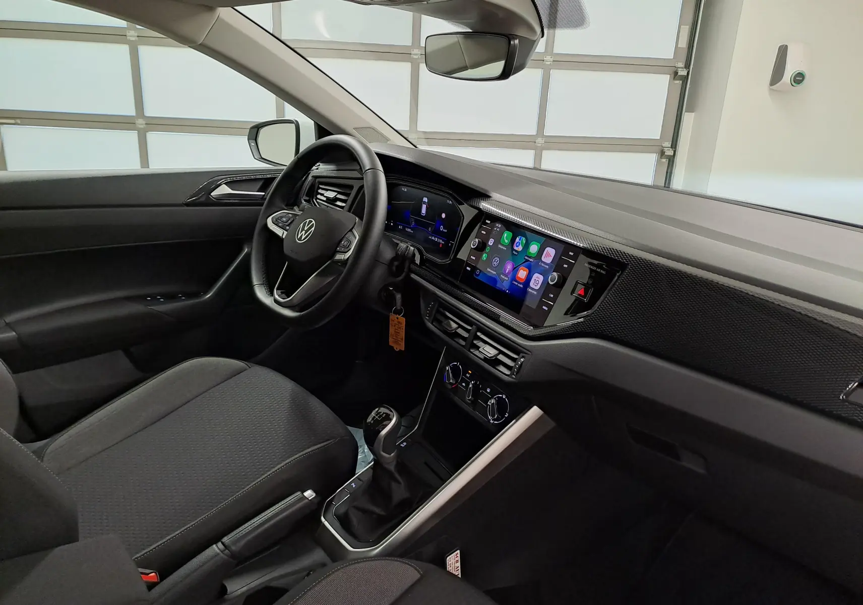 Vue intérieure côté conducteur de la Volkswagen Polo 2024 blanc pur, avec tableau de bord numérique et écran tactile central.