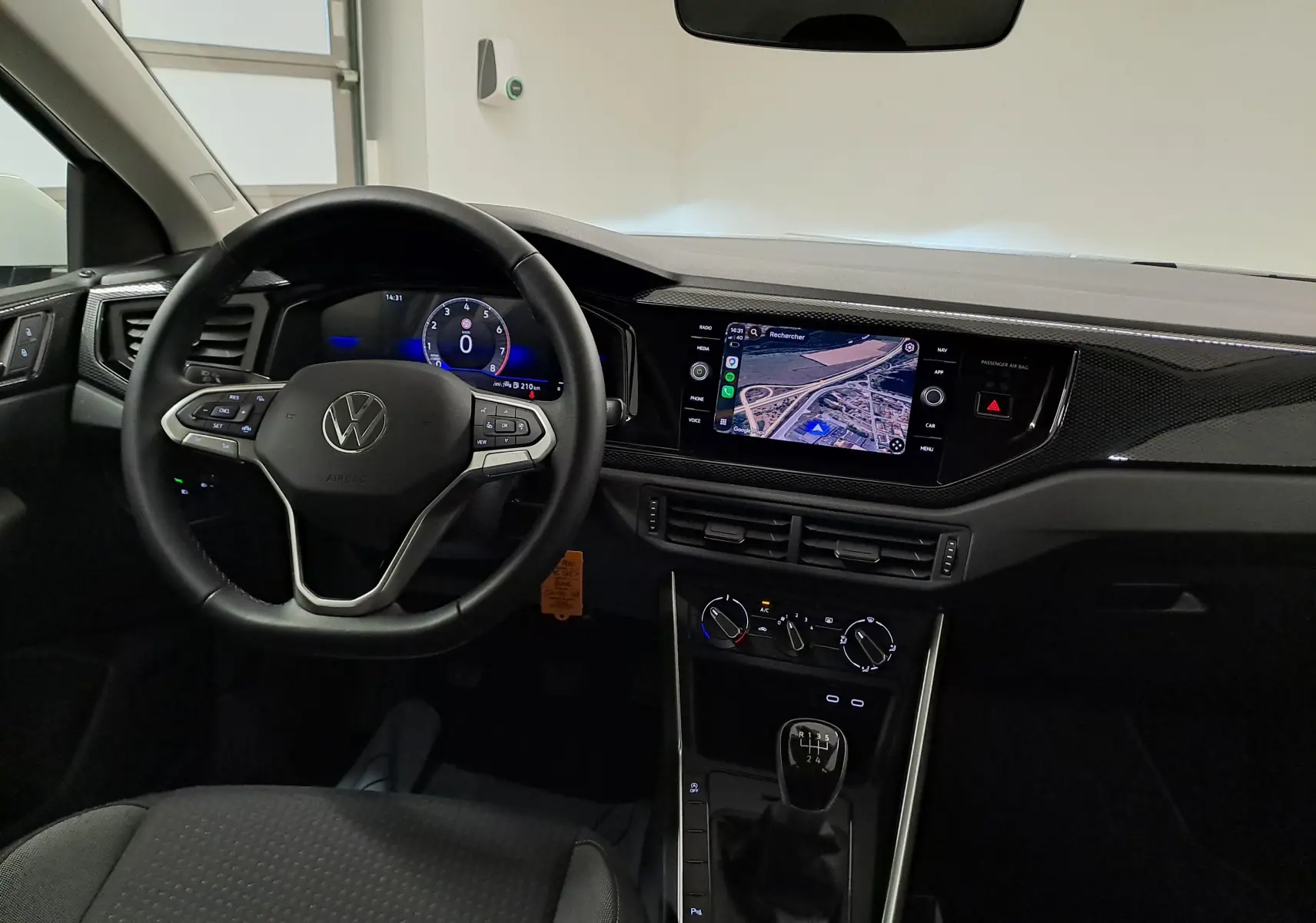 Vue intérieure avant du tableau de bord de la Volkswagen Polo blanche 2024 avec volant multifonction et écran tactile central.