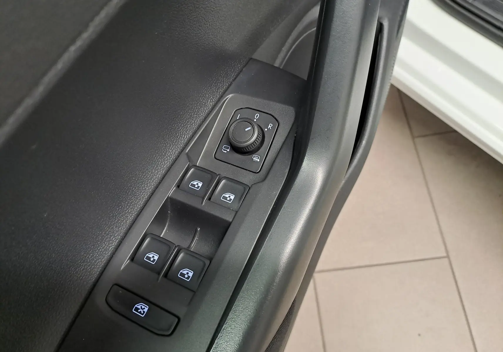 Vue rapprochée des commandes de lève-vitres et réglage des rétroviseurs côté conducteur d'une Volkswagen Polo blanc pur 2024.