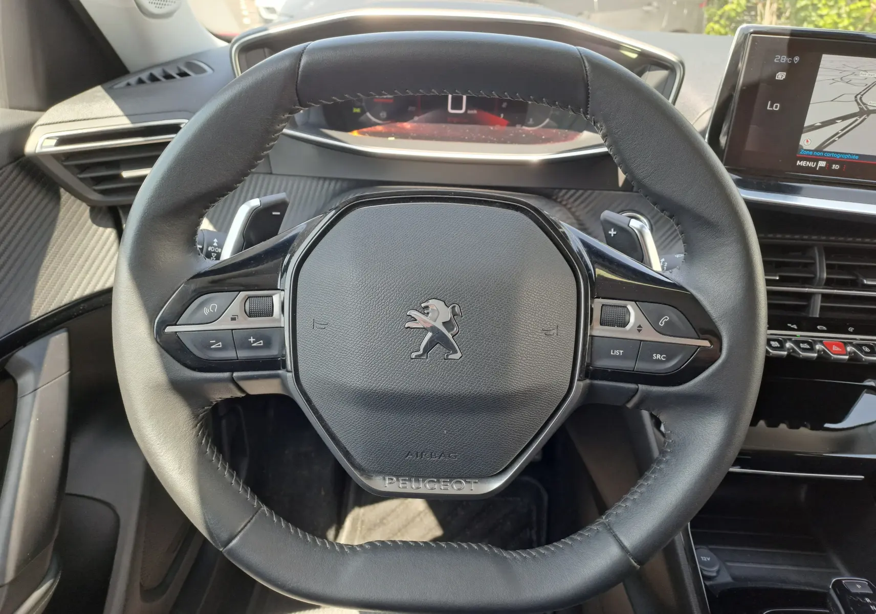 Vue rapprochée du volant cuir noir de la Peugeot 2008 2021 avec commandes intégrées et tableau de bord digital.