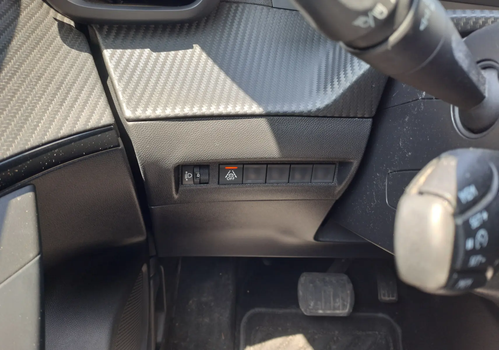 Vue rapprochée du tableau de bord côté gauche du Peugeot 2008 rouge 2021, avec commandes d'éclairage et bouton de désactivation d'assistance.