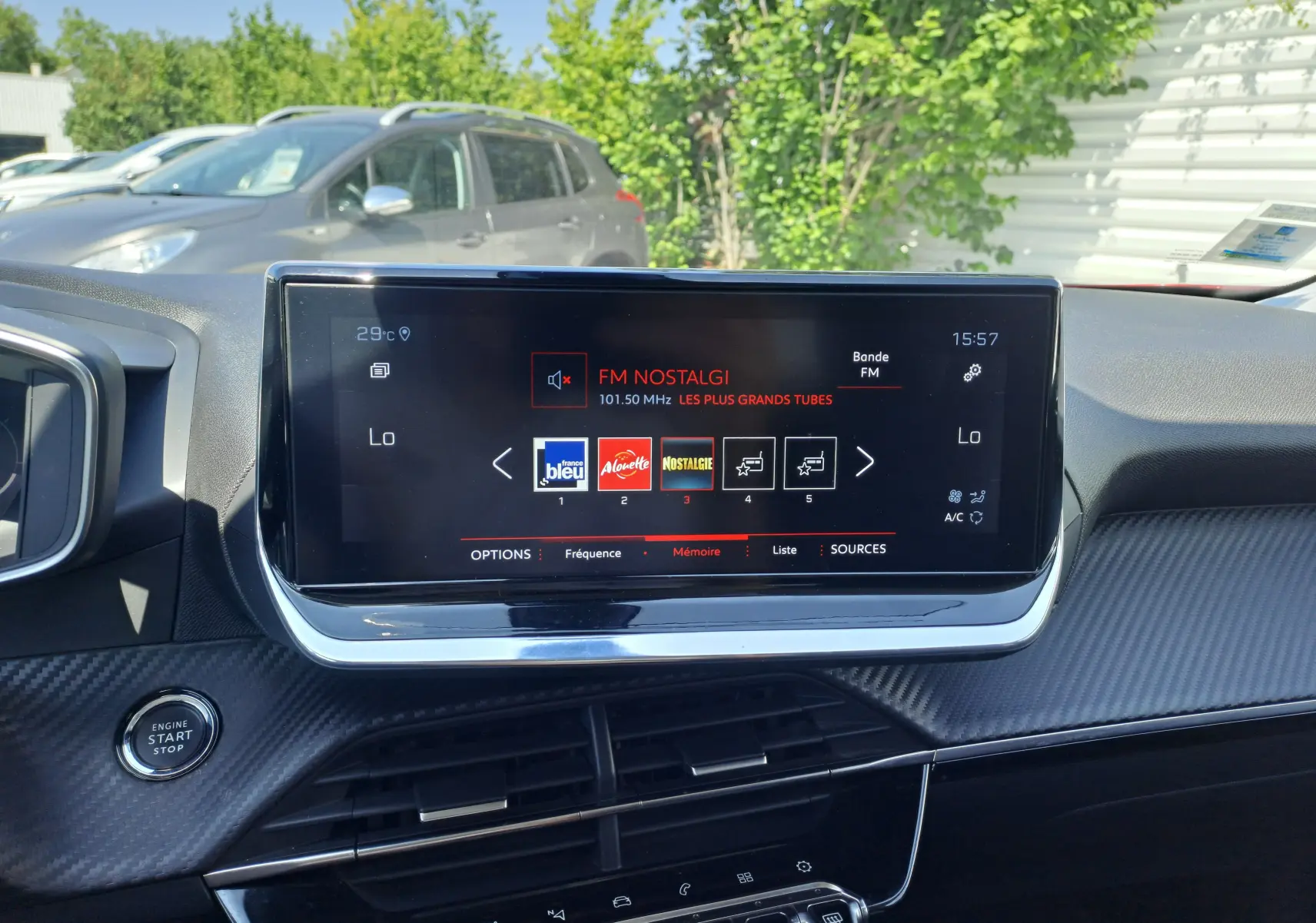 Écran central tactile du tableau de bord d’un Peugeot 2008 rouge, affichant la radio FM Nostalgie à 15h57.