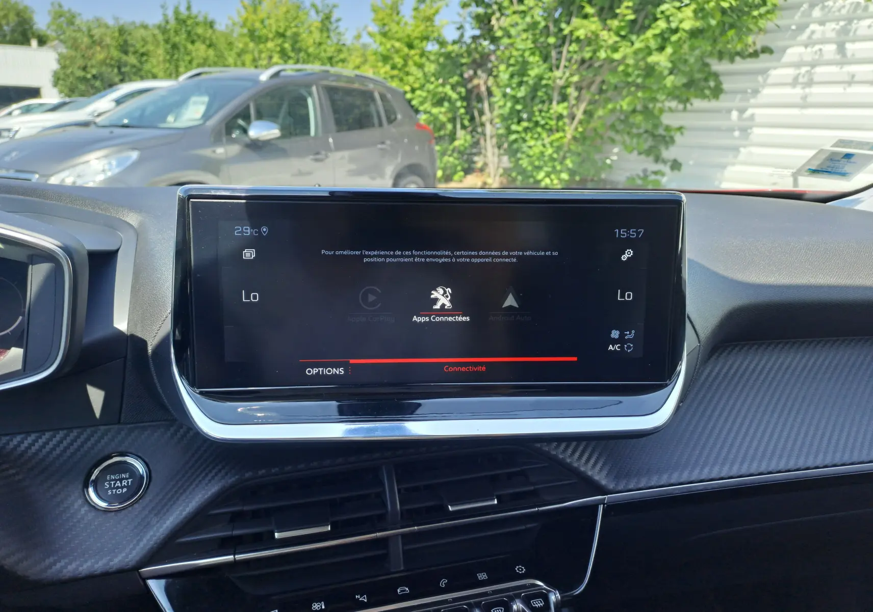 Vue rapprochée de l'écran tactile central et du tableau de bord intérieur noir du Peugeot 2008 rouge, avec bouton start visible.