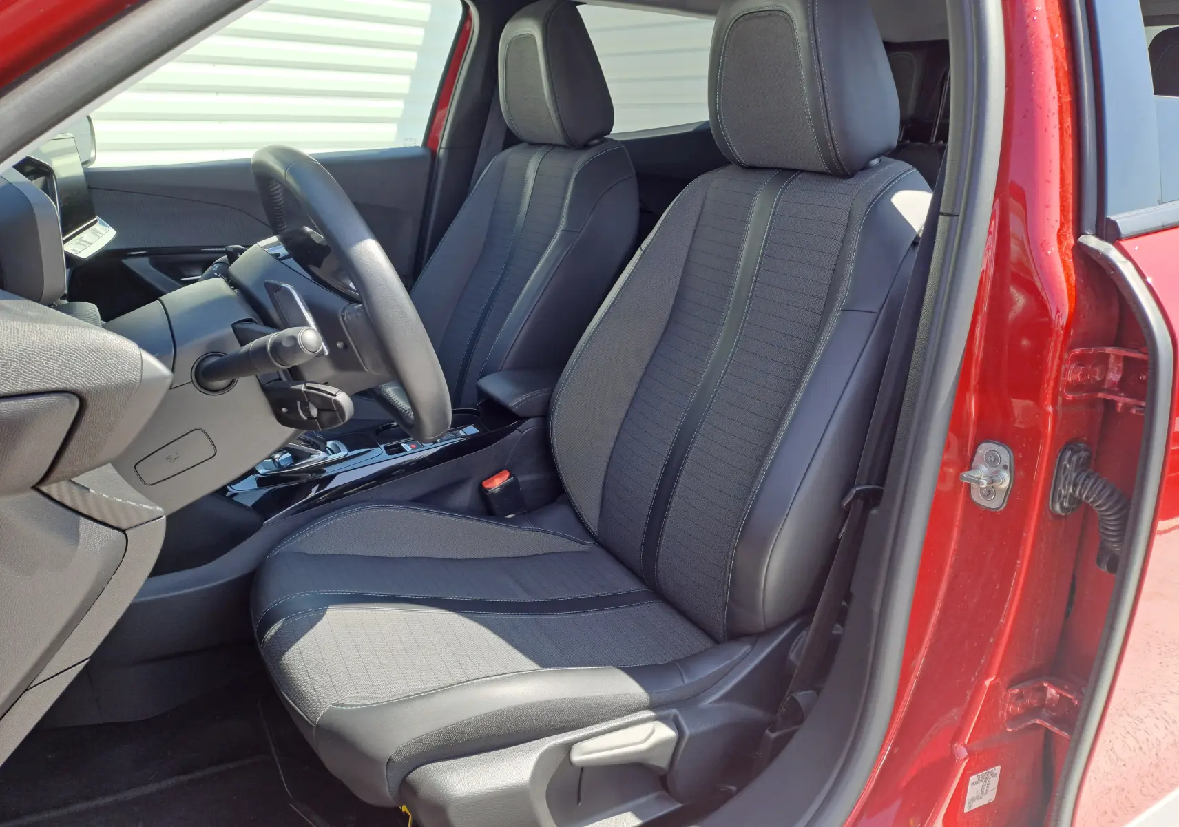 Intérieur avant droit du Peugeot 2008 rouge 2021, sièges tissu noir et console centrale avec boîte auto visible.