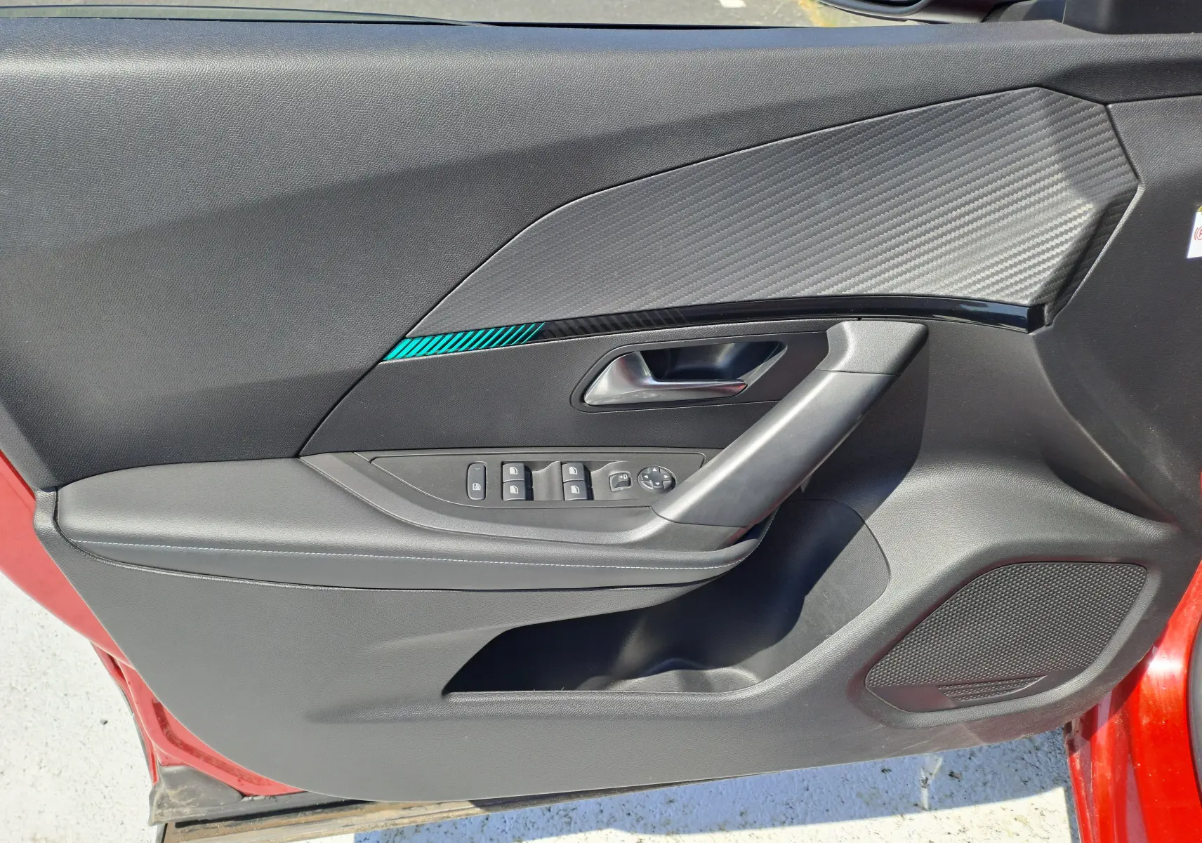Vue côté gauche de la porte intérieure noire avec insert décoratif et commandes électriques sur Peugeot 2008 rouge 2021