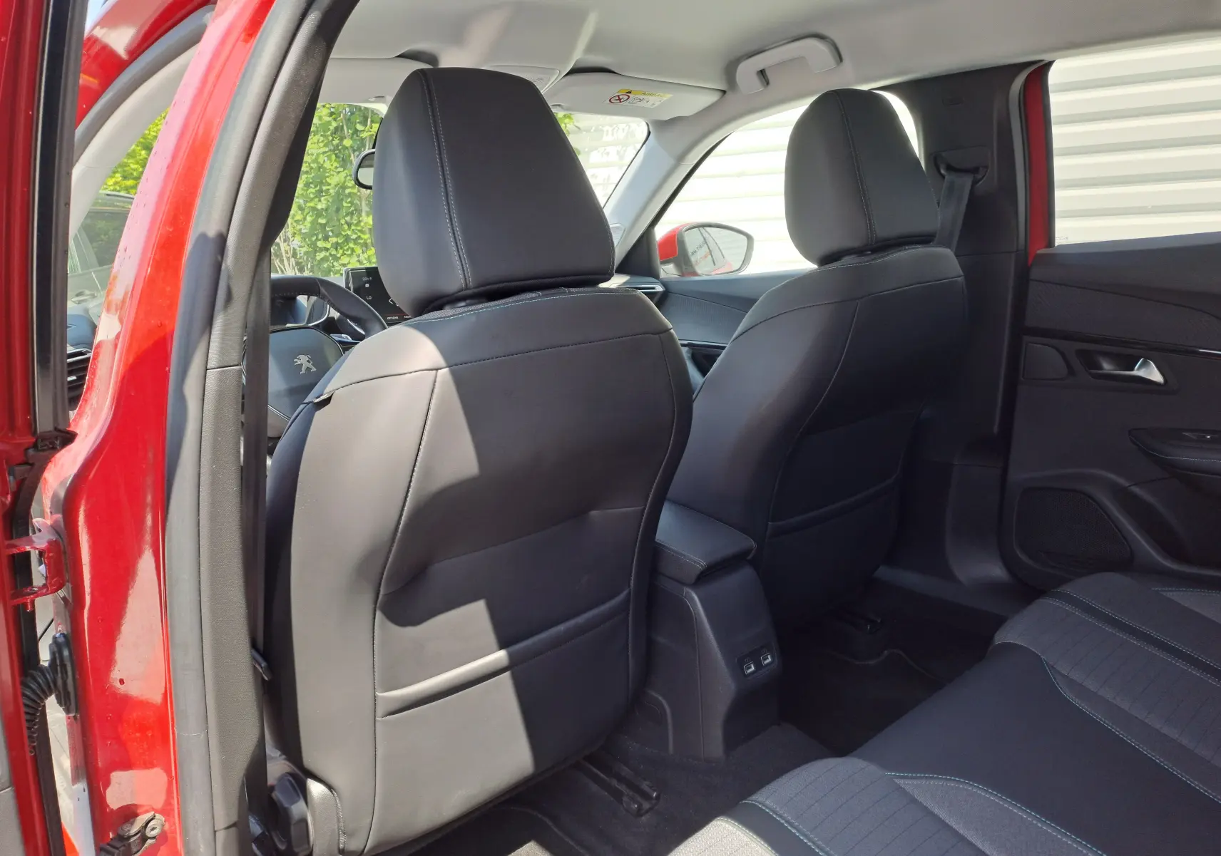 Vue arrière intérieure du Peugeot 2008 rouge 2021, sièges avant en cuir noir et console centrale avec ports USB.