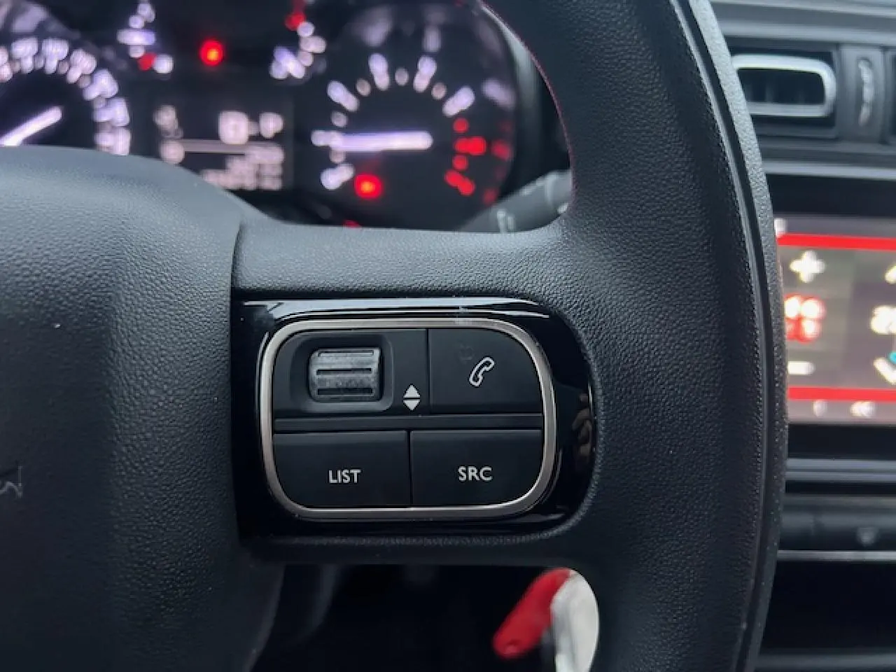 Gros plan sur les commandes audio au volant à droite du tableau de bord d'une Citroën C3 Shine 2023 noir toit rouge.