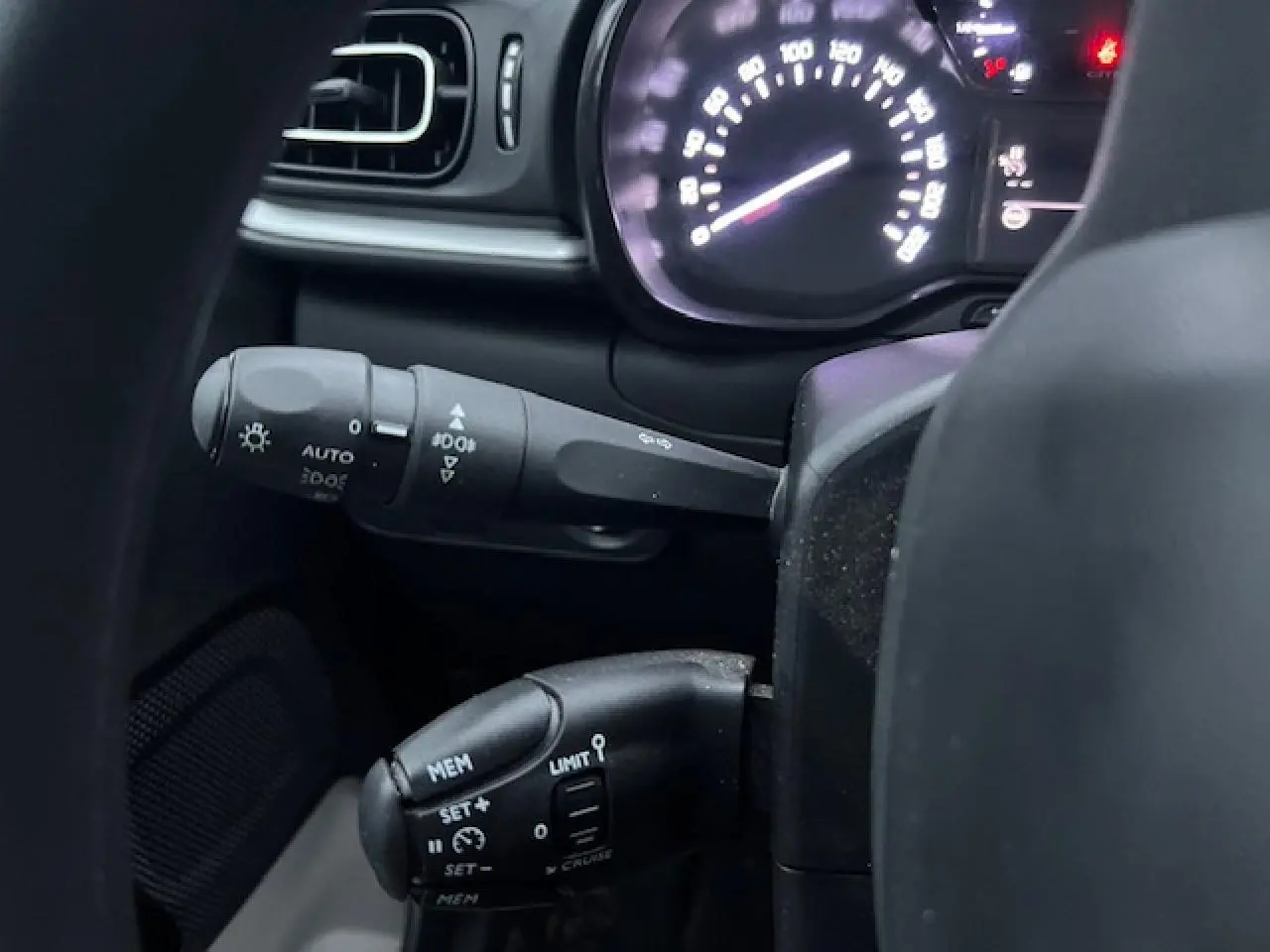Gros plan sur les commandes au volant et le compteur lumineux d'une Citroën C3 Shine 2023 noir toit rouge.