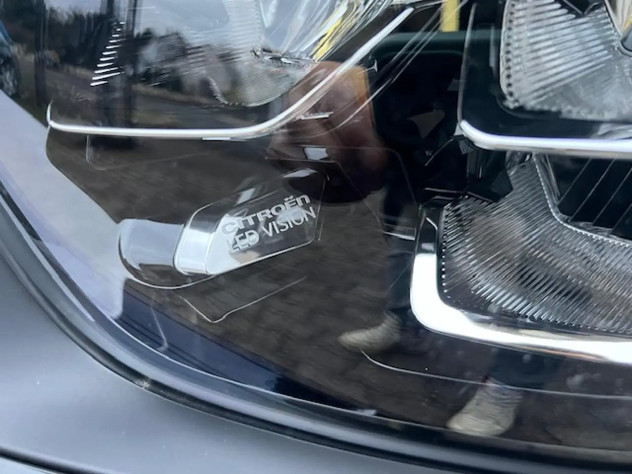 Gros plan sur le phare avant LED d'une Citroën C3 Shine noire au toit rouge, mettant en valeur l'inscription "Citroën LED Vision".