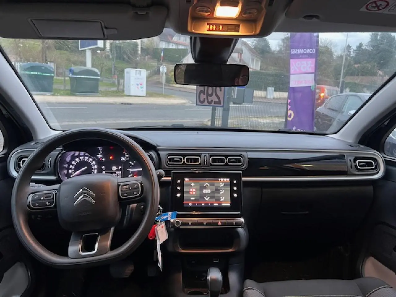 Vue intérieure avant du tableau de bord noir de la Citroën C3 Shine 2023 avec volant multifonction et écran tactile central.