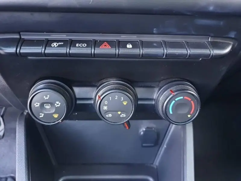 Commandes manuelles de climatisation et boutons fonctionnels du tableau de bord du Dacia Duster blanc 2021.