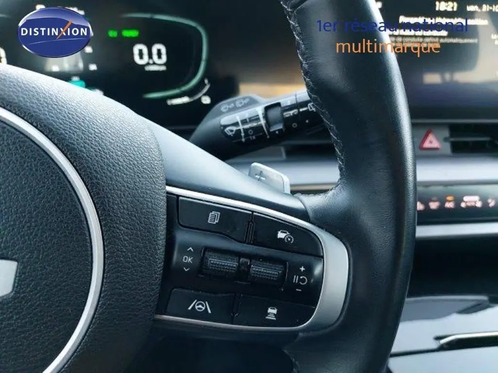 Gros plan sur le volant cuir noir du Kia Sportage 2024 avec commandes intégrées et tableau de bord numérique en arrière-plan.