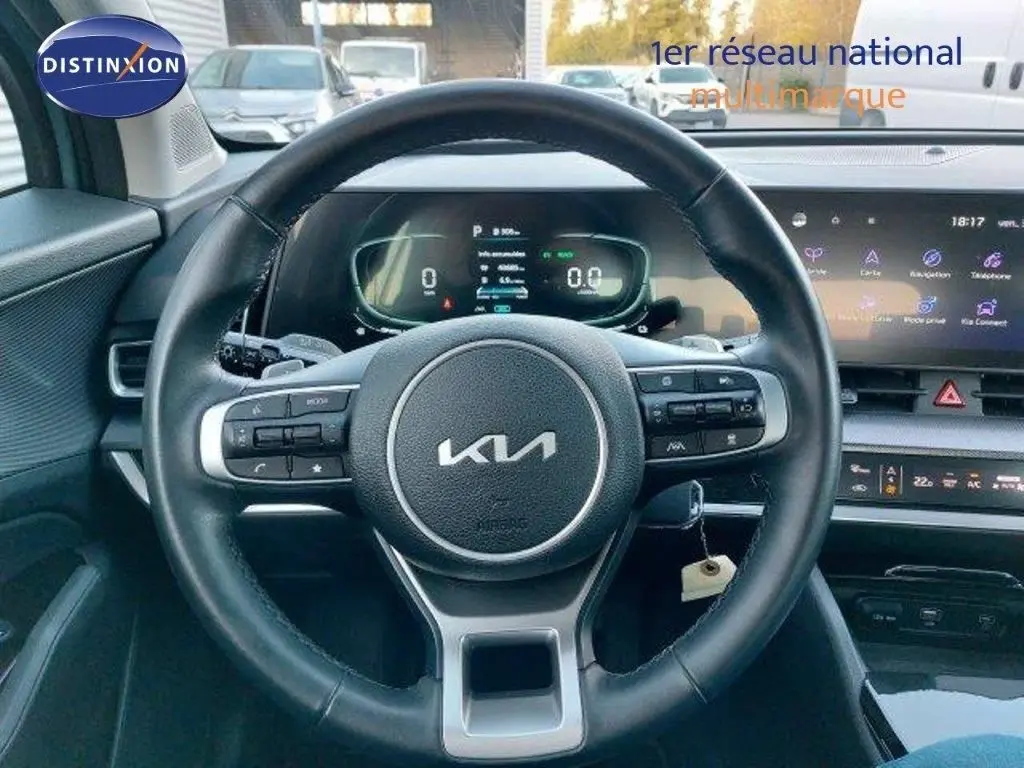 Vue intérieure centrée sur le volant noir du Kia Sportage 2024 avec tableau de bord digital et écran tactile.