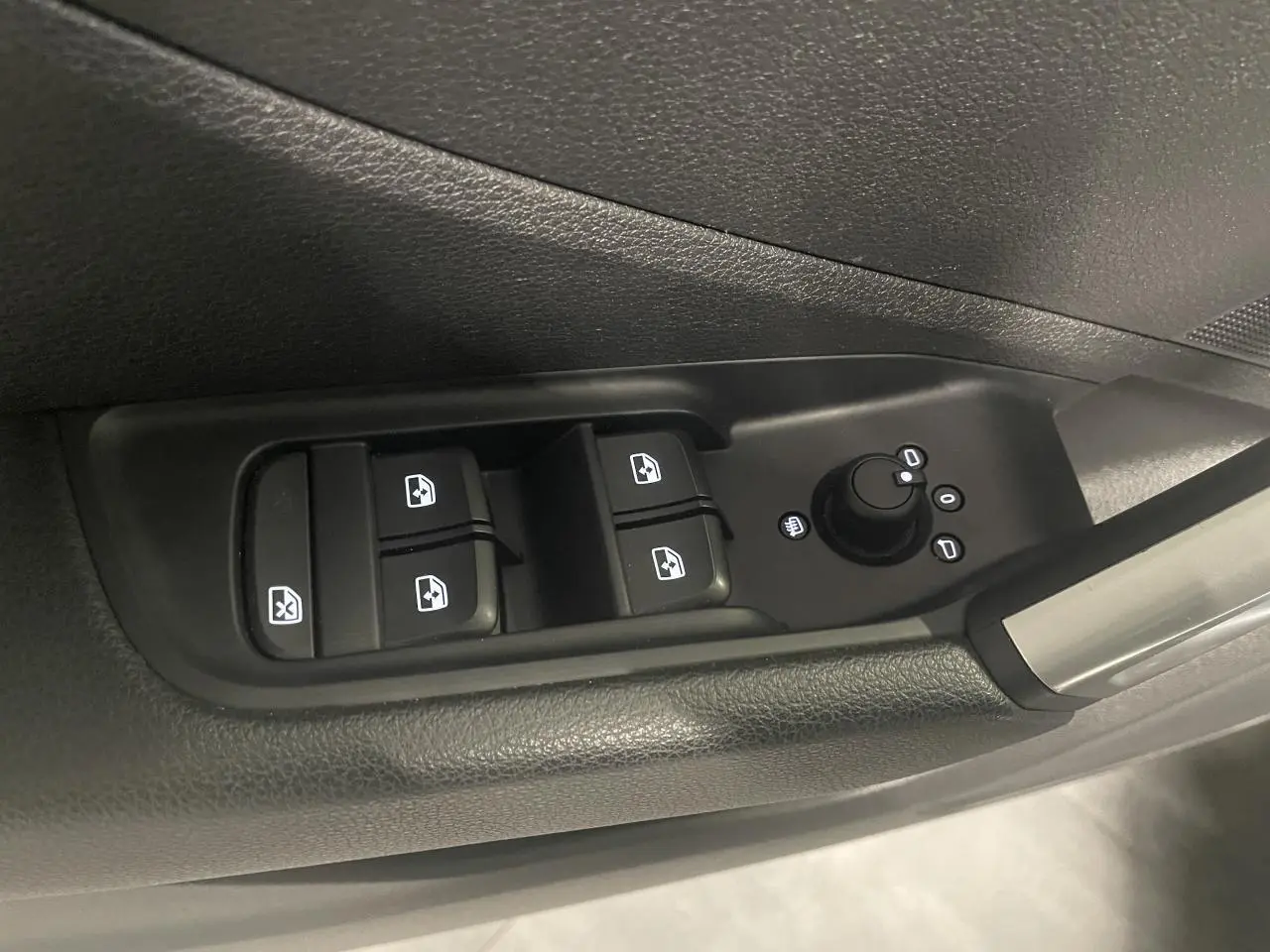 Gros plan sur les commandes de lève-vitres et réglage des rétroviseurs côté conducteur de l'Audi Q2 noir métallisé 2023.